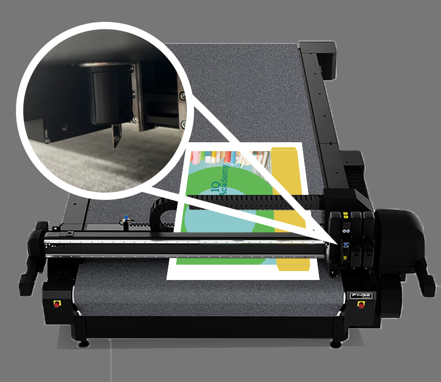 Flatbed cutter with printed sheet laying on surface ready to be cut. Inset shows closeup of single blade.